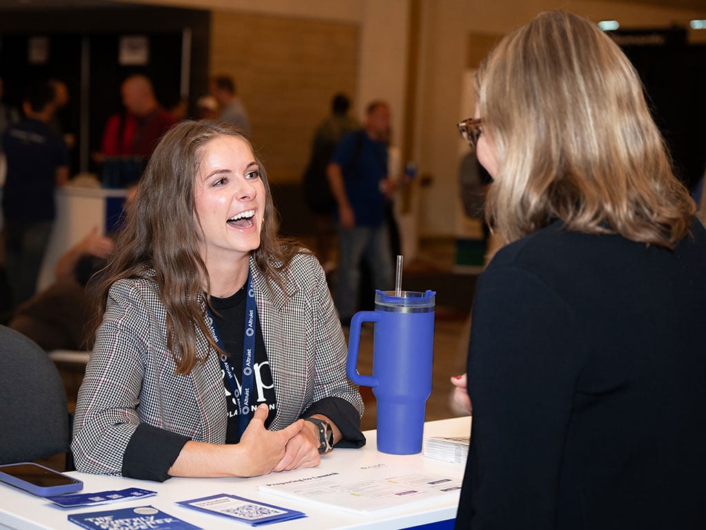 XYPN's Senior Business Development Specialist smiling while talking with an XYPN LIVE 2023 attendee on Exhibit Hall Day